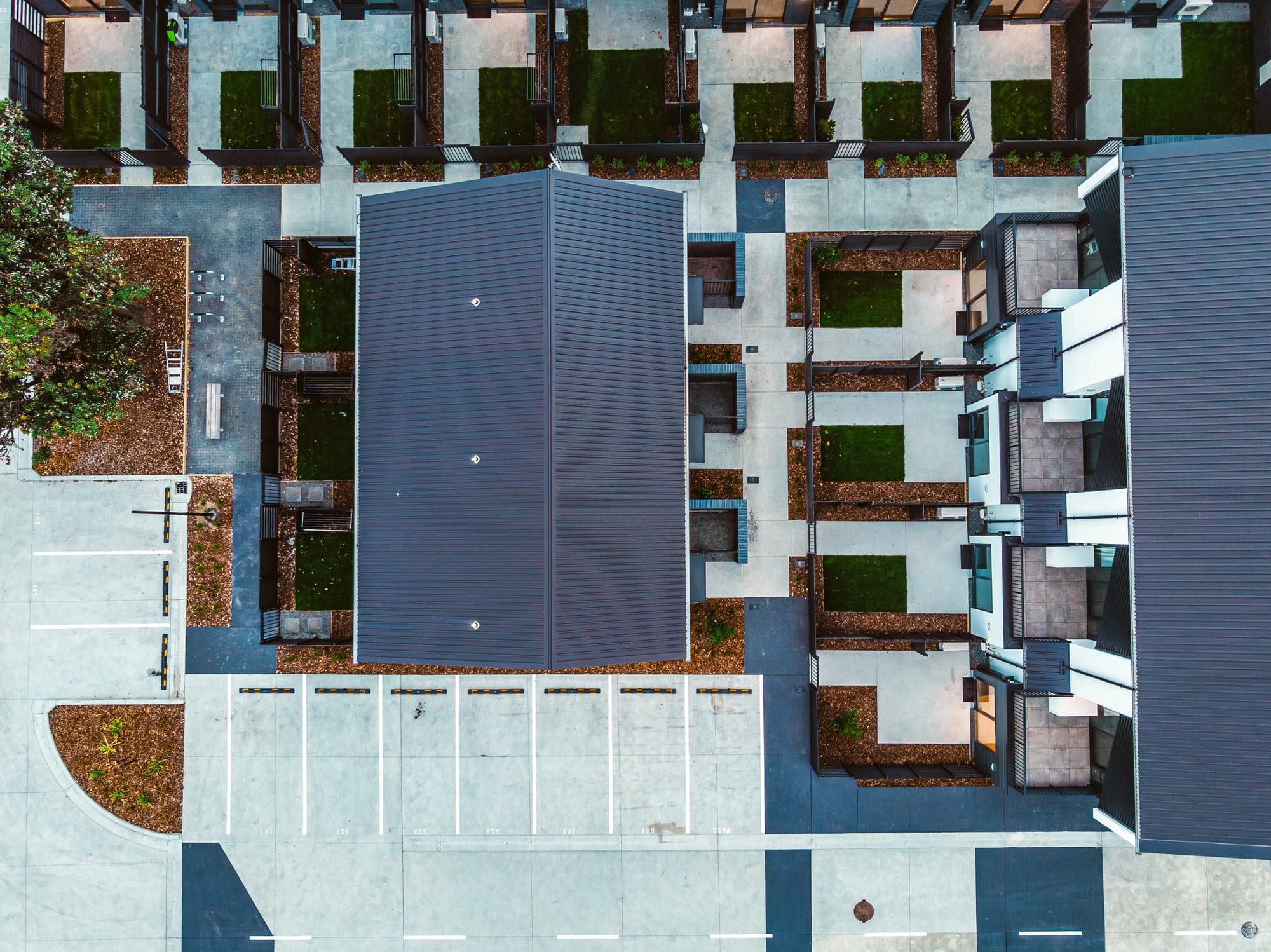 Straight down over the site — the concrete paths, parking and private courtyards laid out between the units.