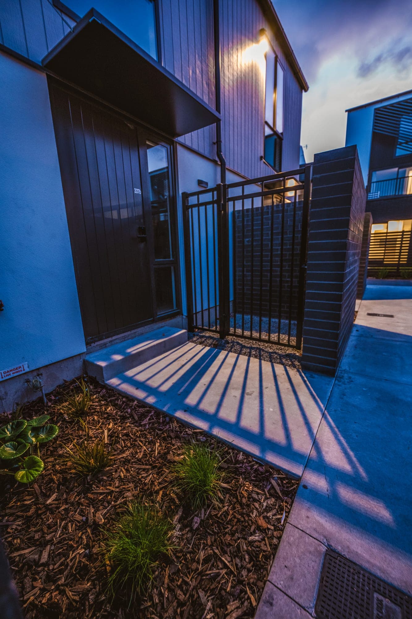 A concrete entry path and step up to a unit, with a planted garden bed alongside.