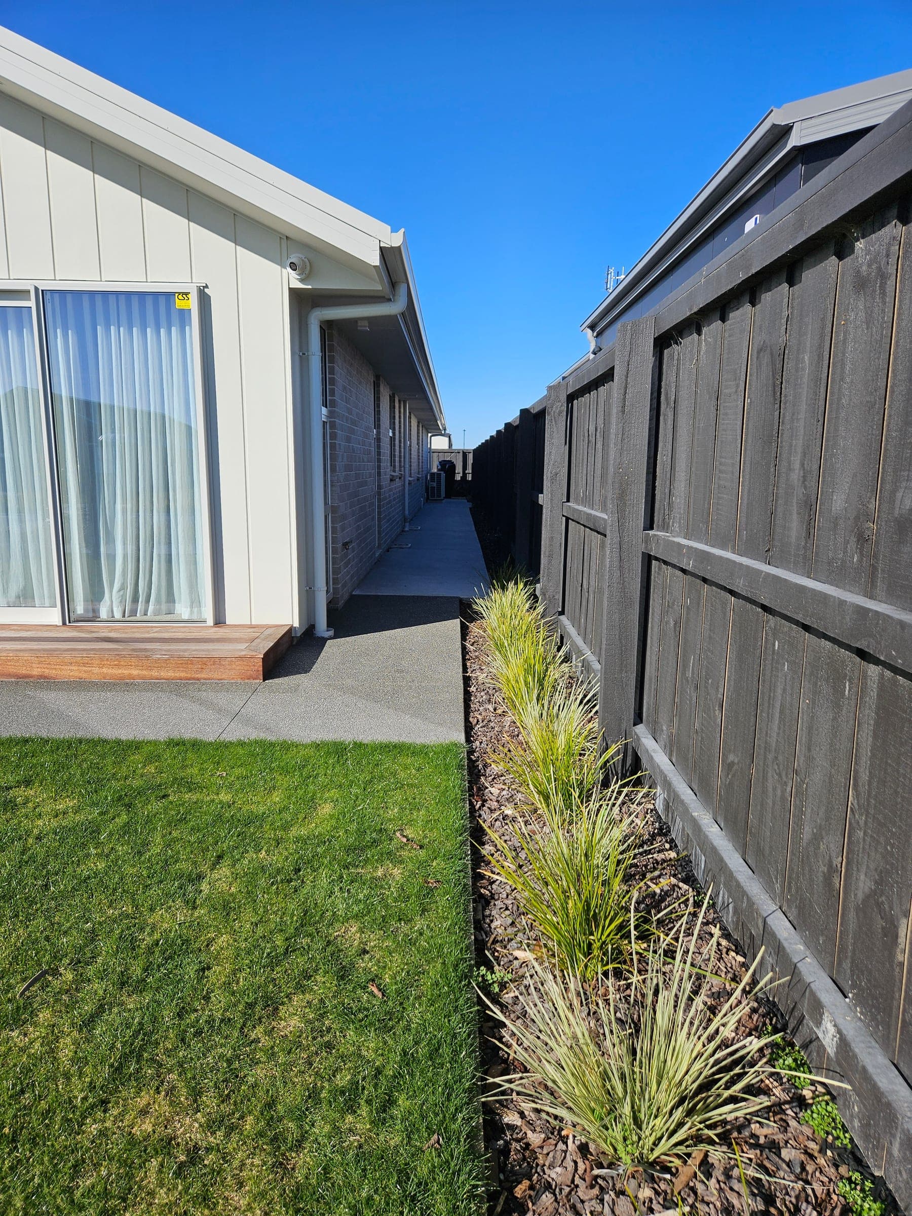 Paver paths and a pergola down the side, with planting and lawn by Landscape Brothers.